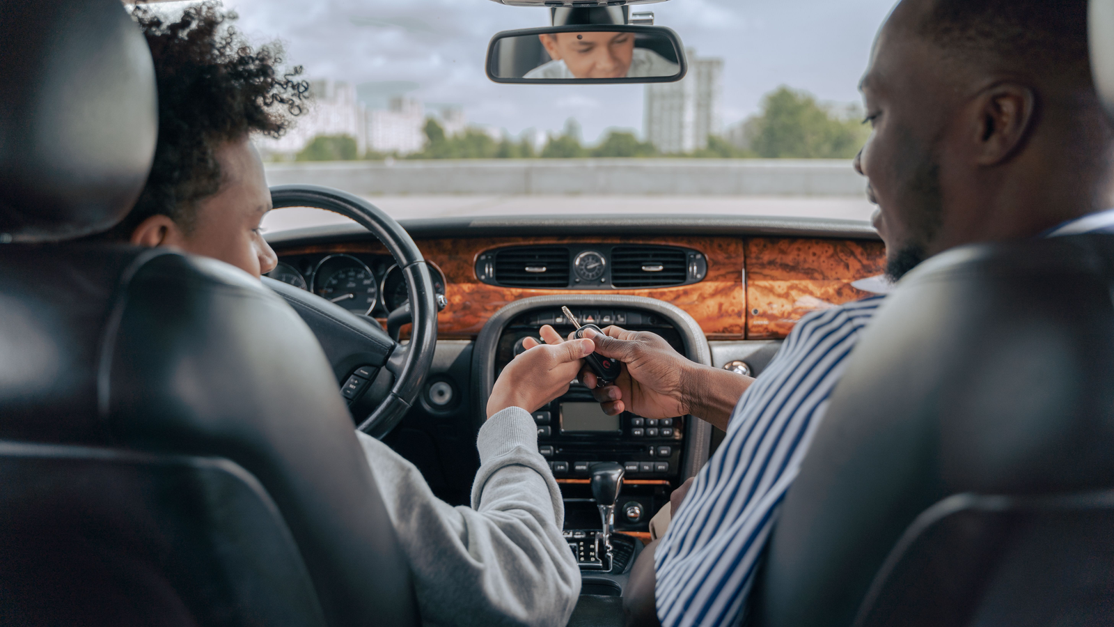 Zwei Personen auf den Vordersitzen eines Autos bei einer Schlüsselübergabe
